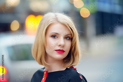 Blond girl with make-up and clean skin on a city street with bokeh on background.Female portrait on the street close-up.