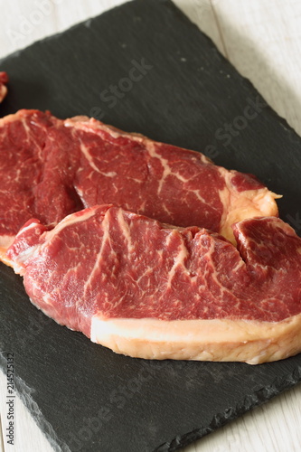 Sirloin steak beef joints on a slate cutting board on a grey wood background