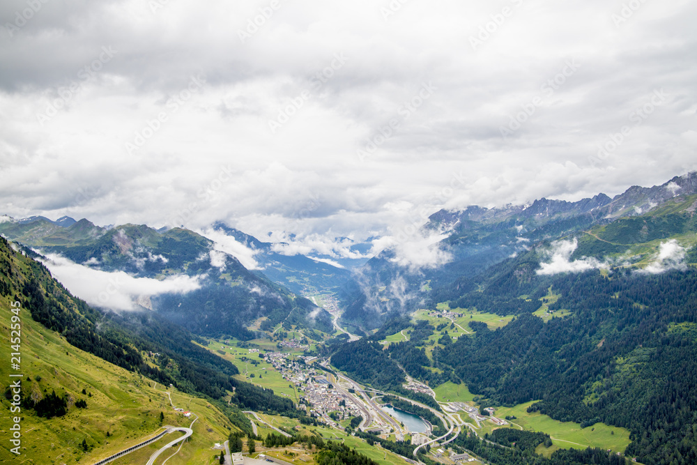 Obraz premium View from the top of the San Gottardo Pass to the mountain valley against the background of passing clouds