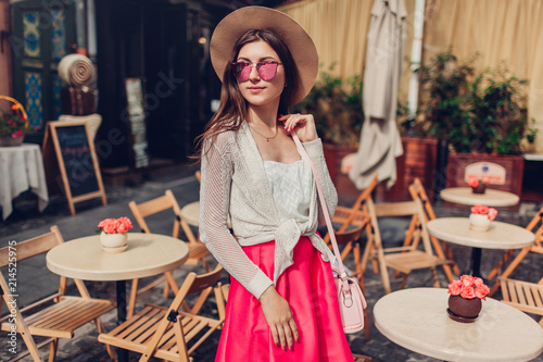 Young woman wearing stylish outfit with accessories outdoors. Portrait of fashionable woman in cafe photo