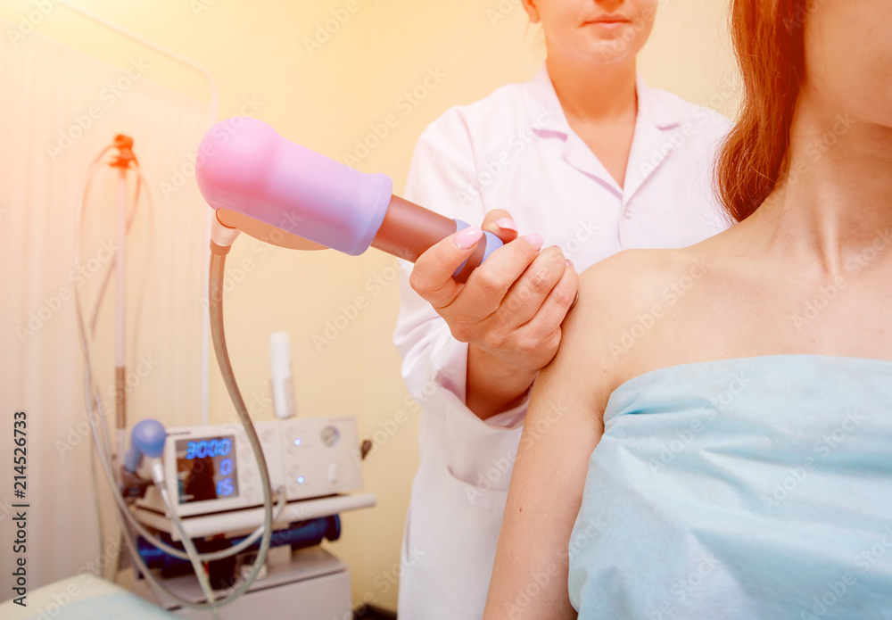 Obraz premium Shock wave therapy. The magnetic field, rehabilitation. Physiotherapist doctor performs surgery on a patient's shoulder