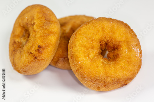 An assortment of donuts, powder donuts, chocolate donuts and plain donuts and a table waiting to be eaten