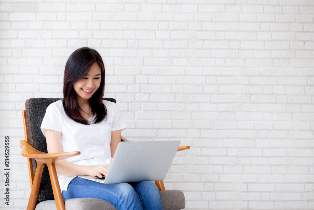 Beautiful of portrait asian young woman working online laptop sitting on chair on cement brick white background, girl using notebook computer, business concept. Beautiful of portrait asian young woman working online laptop sitting on chair on cement brick white background, girl using notebook computer, business concept.
