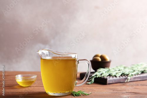 Jug with fresh rosemary oil on table