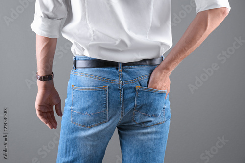 Man in stylish blue jeans on grey background