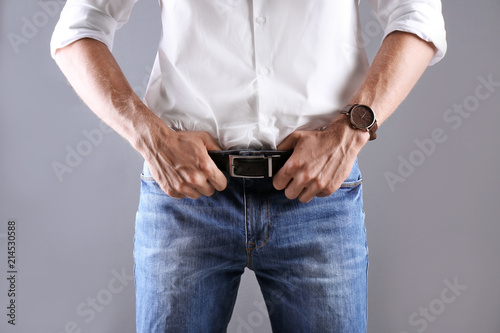 Man in stylish blue jeans on grey background