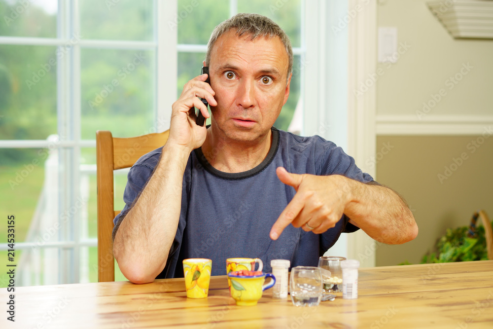 Caucasian man, alone, sit at a table, day, worrying about the pills he is supposed to take. Caucasian man, alone, sit at a table, day, worrying about the pills he is supposed to take.