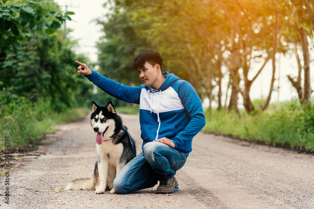 Man and dog Siberian huskies concept. Asian young man with his dog sitting on street in the park. Man and dog Siberian huskies concept. Asian young man with his dog sitting on street in the park.