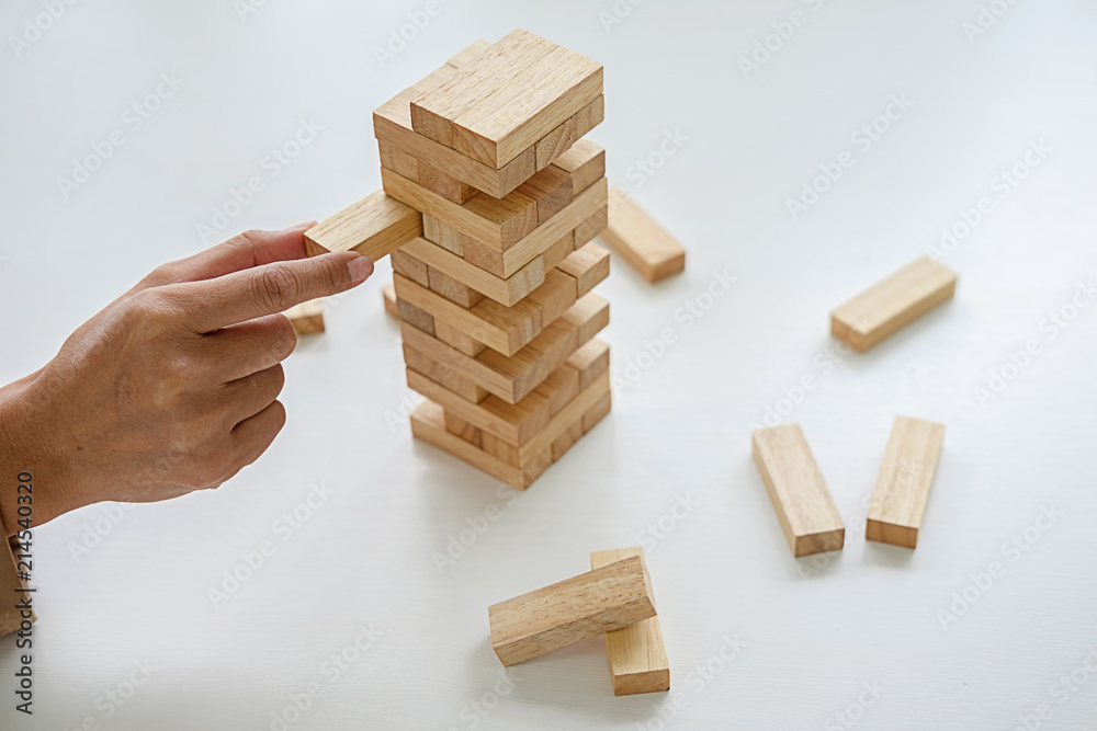 Hand of business people planning, risk and strategy in business.Businessman gambling placing wooden block on a tower. Hand of business people planning, risk and strategy in business.Businessman gambling placing wooden block on a tower.
