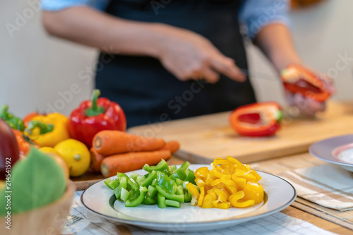 Closeup Bell pepper over the photo blurred of chef are cut the bell pepper on the Chopping board in modern kitchen, diet and healthy food concept