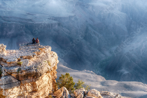 Couple Is Seating On The Edge of Cliff and Watching of Sunrise at Grand Canyon from Mather Point