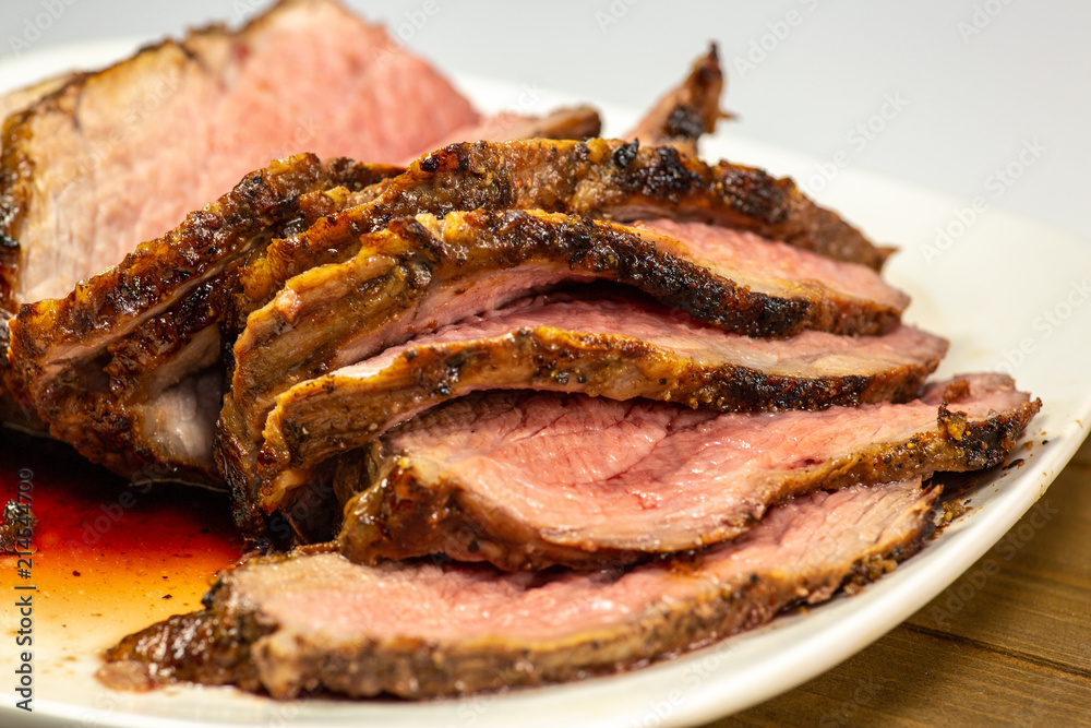 Grilled tri tip steak sliced on a white plate on the kitchen table