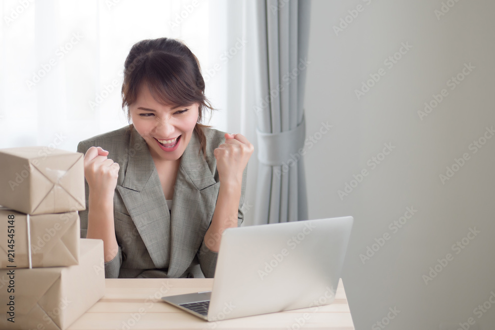 excited asian woman working with her laptop computer and courier parcel box; portrait of excited, happy woman business owner with business success or profit concept; adult asian chinese woman model excited asian woman working with her laptop computer and courier parcel box; portrait of excited, happy woman business owner with business success or profit concept; adult asian chinese woman model