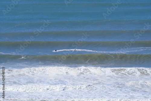 Jet ski towing a surfer between massive waves after a storm on the Gold Coast
