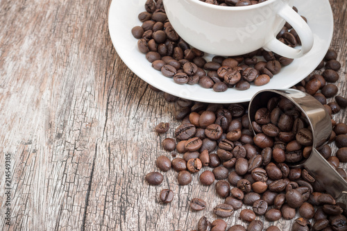 Coffee beans in white cup on wooden table with copy space.