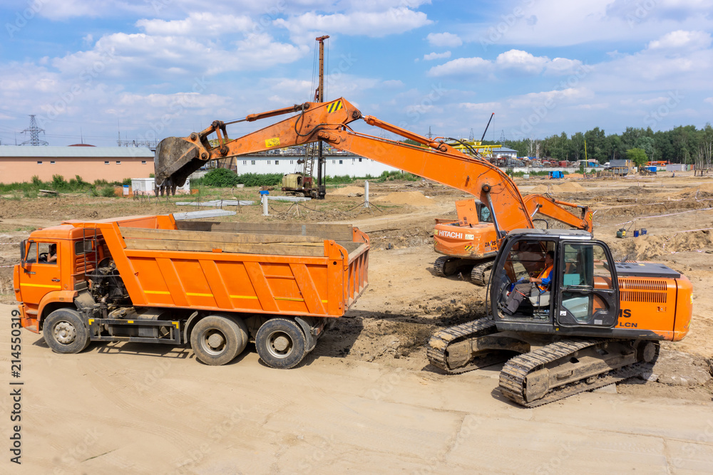 Two excavators load the earth into a dump truck Two excavators load the earth into a dump truck