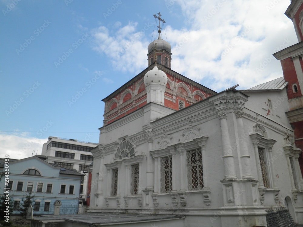 old red-and-white church in the middle of the city against a blue sky with white clouds
