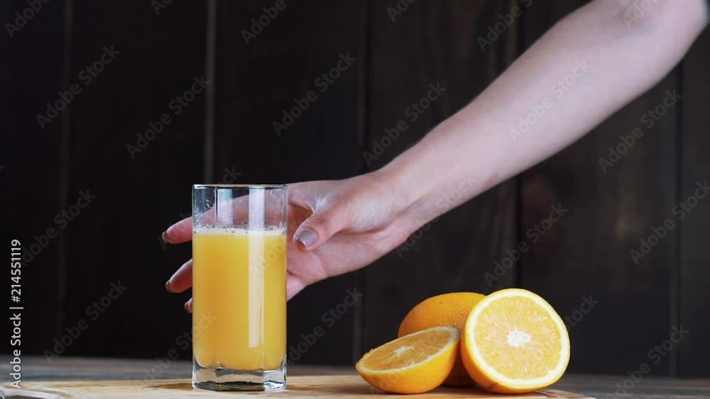 Freshly squeezed orange juice in a glass. Pour, squeeze orange juice. On a wooden background. Freshly squeezed orange juice in a glass. Pour, squeeze orange juice. On a wooden background.