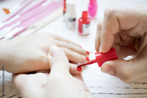 mom does baby manicure on white wooden table, beautiful nails