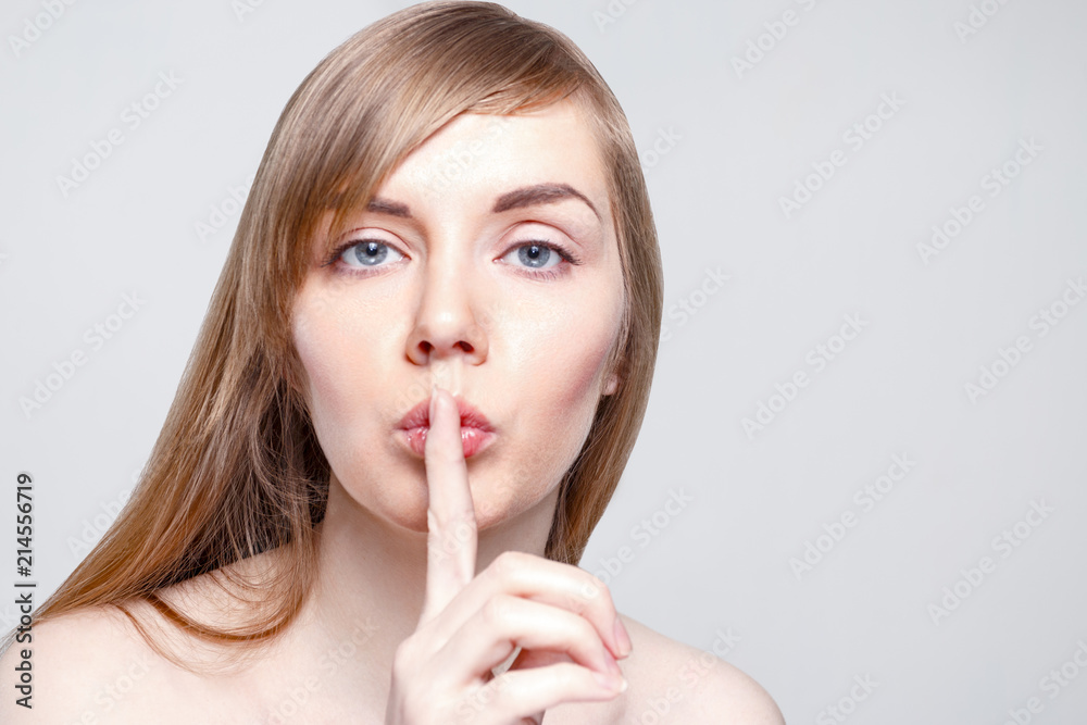 Beautiful young woman with make-up shows quiet gesture in studio, close up portrait Beautiful young woman with make-up shows quiet gesture in studio, close up portrait