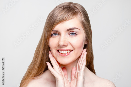 Happy young woman with make-up smiles in studio, close up portrait