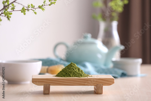 Wooden stand with powdered matcha green tea on table photo