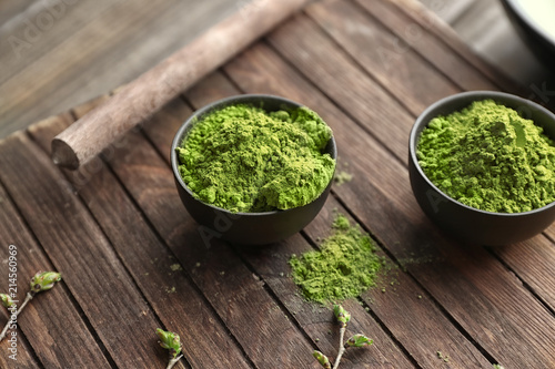 Bowls with powdered matcha green tea on wooden board