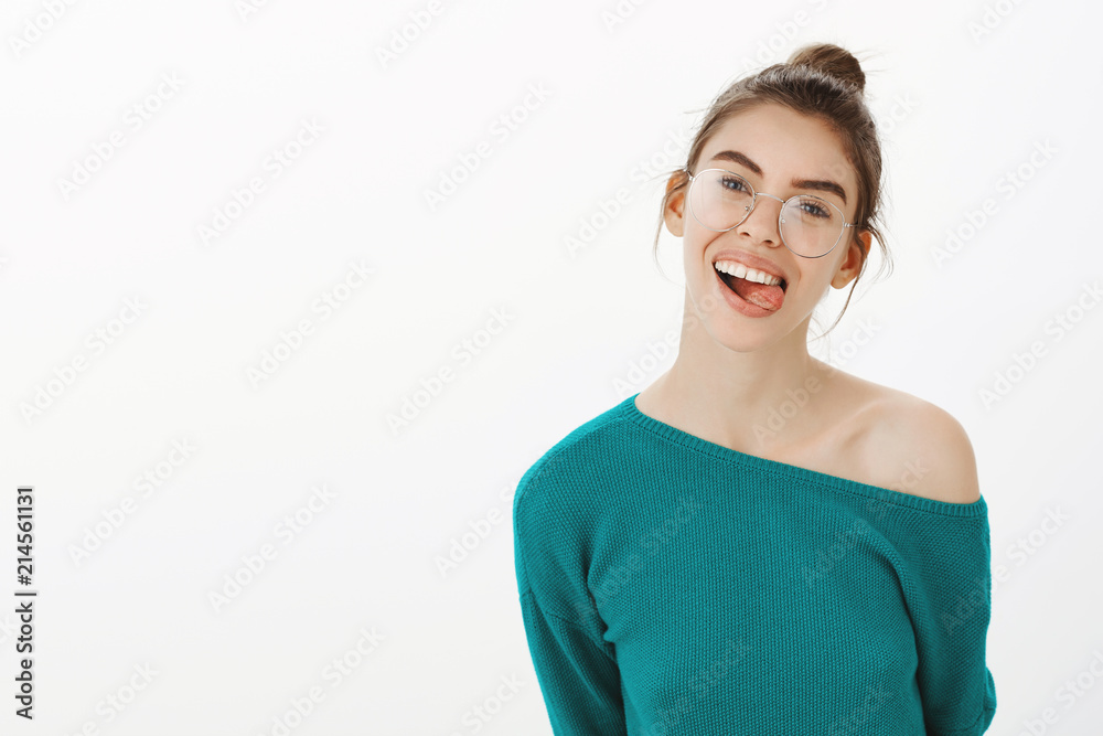 Be yourself always. Portrait of carefree happy caucasian woman in glasses, smiling joyfully while showing tongue, holding hands behind, tilting head, feeling childish and playful over gray wall Be yourself always. Portrait of carefree happy caucasian woman in glasses, smiling joyfully while showing tongue, holding hands behind, tilting head, feeling childish and playful over gray wall