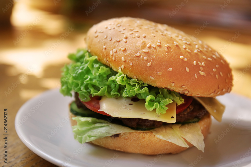 Plate with tasty cheeseburger on table Plate with tasty cheeseburger on table