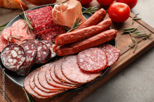 Plate with assortment of delicious deli meats on wooden board photo