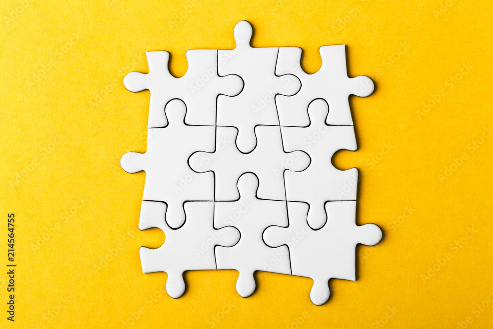Fototapeta premium White details of puzzle on yellow background.