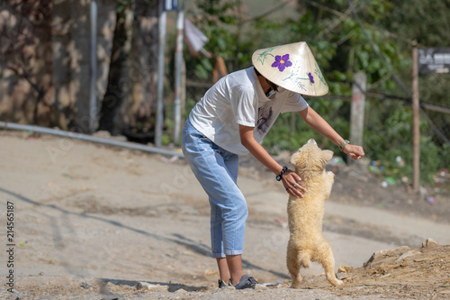 Young Vietnamese woman plays with stray dog in Sa Pa region in Vietnam.