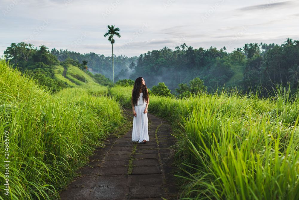 Young beautiful woman walking on Campuhan Ridge way of artists, in Bali, Ubud. Beautiful calm sunny morning