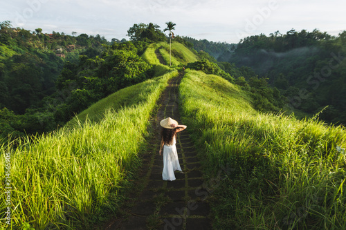 Young beautiful woman walking on Campuhan Ridge way of artists, in Bali, Ubud. Beautiful calm sunny morning photo