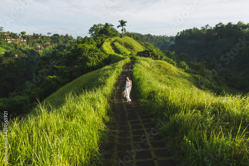 Young beautiful woman walking on Campuhan Ridge way of artists, in Bali, Ubud. Beautiful calm sunny morning photo