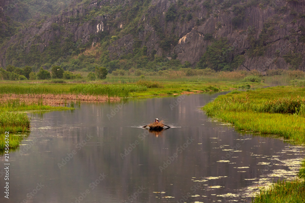 Beautiful landscape in Ninh Binh and the woman boat driver, Vietnam Beautiful landscape in Ninh Binh and the woman boat driver, Vietnam