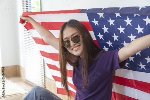 Fashion portrait of Hipster Asian woman wearing sunglasses and holding the American flag with smiling face.