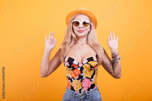 Cool beautiful young woman wearing eyewear glasses mediting in studio over yellow background