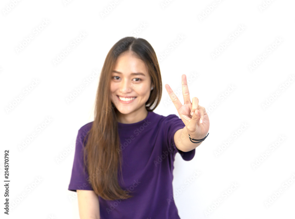 Portrait of a young smiling Asian woman showing peace gesture with white background Portrait of a young smiling Asian woman showing peace gesture with white background