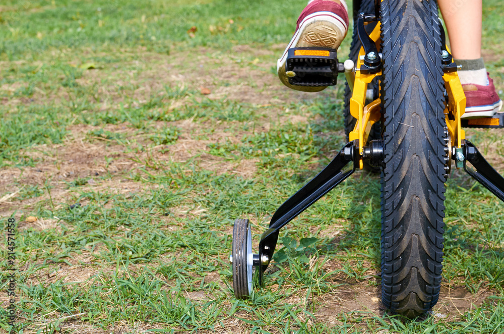 Obraz premium Boy on kids yellow bicycle in park studies to ride