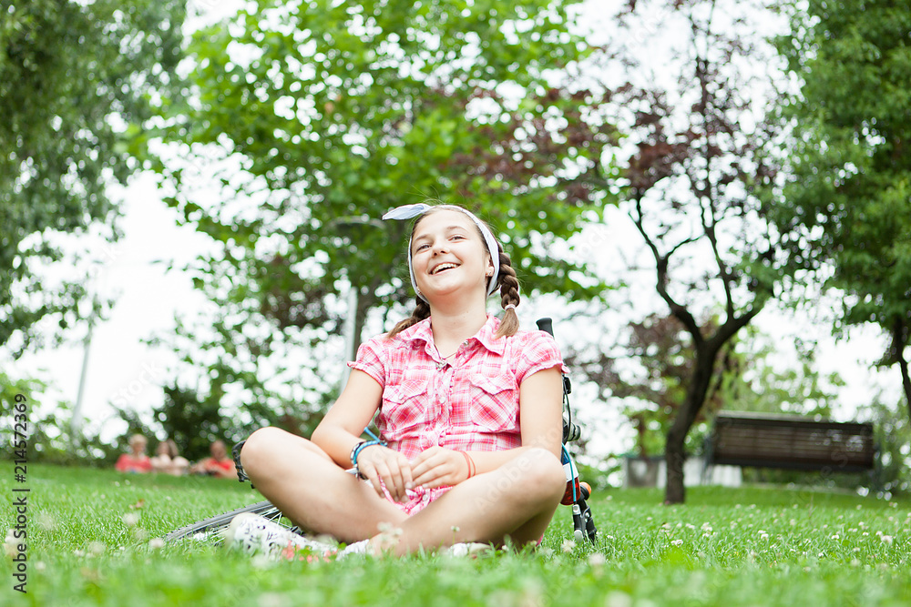 Happy teenager girl sitting on the grass in the park next to her bicycle Happy teenager girl sitting on the grass in the park next to her bicycle