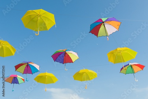 Symbol of summer  many open multi-colored umbrellas on sky background.