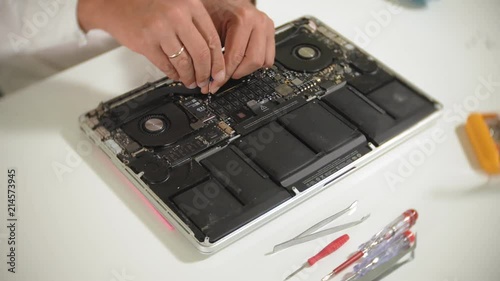 A man is repairing a laptop. The concept of computer repair. Close up of man repair laptop motherboard with a screwdriver. Maintenance of the hardware of the motherboard. Disc holder, computer repair