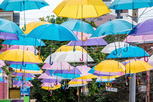 Multicolored umbrellas on the street of a modern city on a holiday day_