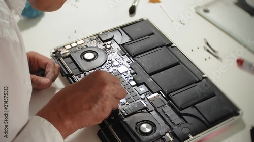 A man is repairing a laptop. The concept of computer repair. Close up of man repair laptop motherboard with a screwdriver. Maintenance of the hardware of the motherboard. Disc holder, computer repair