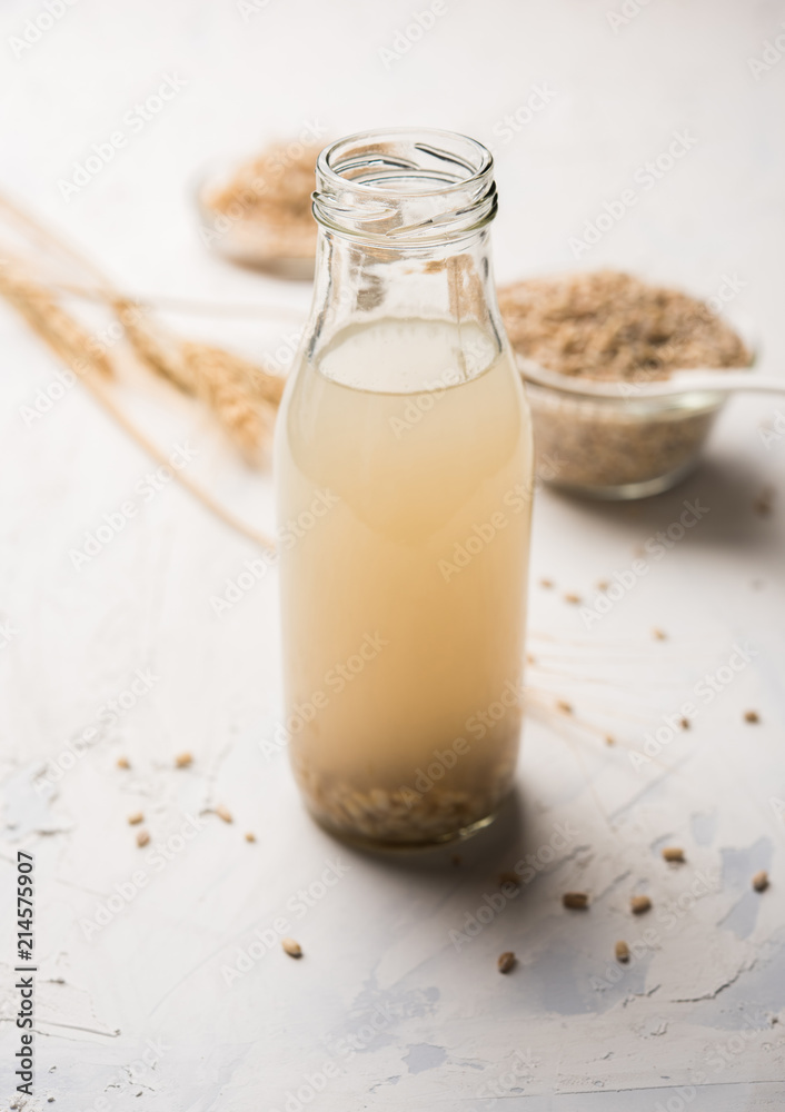 Barley water in glass bottle with raw and cooked pearl barley wheat/seeds. selective focus Barley water in glass bottle with raw and cooked pearl barley wheat/seeds. selective focus