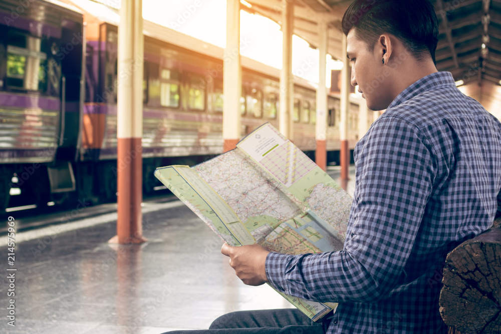 Obraz premium Traveler man sitting at train station and looking on map for travel planning.