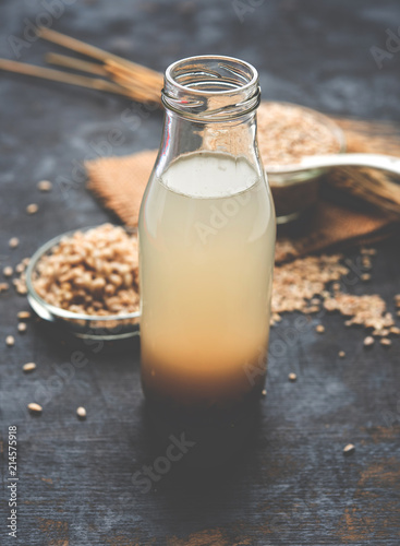 Barley water in glass bottle with raw and cooked pearl barley wheat/seeds. selective focus
