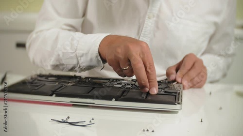 A man is repairing a laptop. The concept of computer repair. Close up of man repair laptop motherboard with a screwdriver. Maintenance of the hardware of the motherboard. Disc holder, computer repair