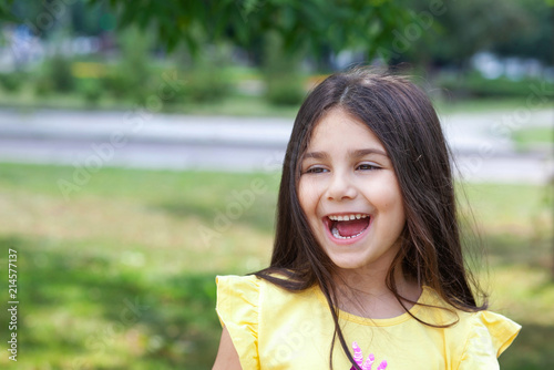 Portrait of a happy smiling child girl outdoors. Cute little girl playing in the park.  © kaganskaya115
